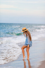 Wall Mural - Adorable young girl with beautiful long hair enjoy tropical beach vacation. The girl on the seashore at sunset