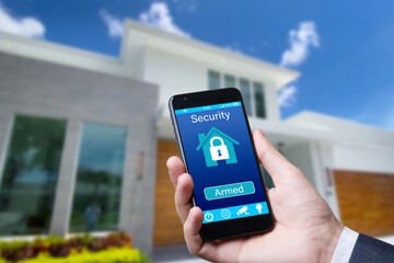 Smartphone with home security app in a hand on the building background.