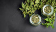 Dried peppermint in a glass jar and a bunch of fresh mint, medicine herb on black background, top view