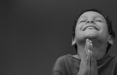 Poster - boy praying to God with hands together on black background with people stock image stock photo	