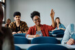 © Drazen - Happy black student raising her hand to ask question during class at university.