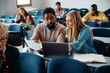 © Drazen - Black adult education teacher assists his student with an assignment during class in classroom.