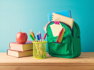 Back to school concept with backpack, pencils and  books on wooden table over blue background