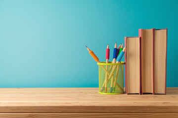 Back to school background with pencils and books on wooden table over blue background