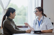 © SOMKID - female doctor with female patient and telling advices sitting at workplace in clinic office, Healthcare and medical concept.