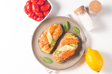 Two tasty open salmon sandwiches with avocado and cucumber. Morning healthy breakfast. Top view.