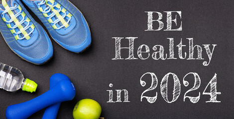 New year 2024 resolutions healthy lifestyle and sport. Be healthy in 2024. Motivation sport goals 2024 with sport equipment shoes, dumbbells, fruit and water bottle on black background