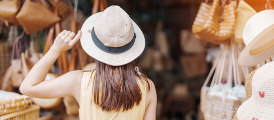 Wall Mural - Young asian woman traveler in dress with hat traveling to wicker shop on Chang Moi Kao Road, Tourist visit at the old city in Chang Mai, Thailand. Asia Travel, Vacation and summer holiday concept