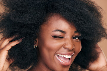 Wall Mural - Portrait, hair and wink with a natural black woman in studio on a brown background for organic cosmetics. Beauty, face and haircare with a happy young afro female person indoor for shampoo treatment