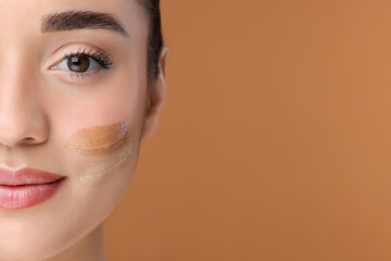 Wall Mural - Woman with swatches of foundation on face against brown background, closeup. Space for text