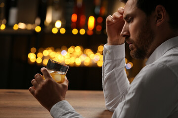 Wall Mural - Man with glass of whiskey against blurred lights, closeup