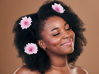 Hair care, flowers and black woman, happy and beauty in studio isolated on a brown background. Smile, floral afro cosmetics or natural African model in organic salon treatment, wellness and hairstyle