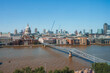 Millennium bridge over river Thames. Financial district with clear sky in background. Buildings in city during sunny day at London.