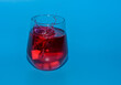 Izolowana szklanka z czerwonym zimnym napojem, wrzucać kostki lodu