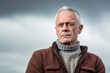 © Leon Waltz - Medium shot portrait photography of a man in his 50s with a somber and deeply sad expression due to major depression wearing a chic cardigan against a sky and clouds background