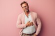 © Leon Waltz - Medium shot portrait photography of a man in his 40s clutching his abdomen due to irritable bowel syndrome wearing a chic cardigan against a pastel or soft colors background