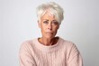 © Leon Waltz - Medium shot portrait photography of a woman in her 50s visibly in discomfort and fatigue from an autoimmune disease like lupus wearing a cozy sweater against a white background