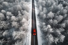 Aerial View Of A Red Car On A Snowy Road Passing Through A Winter Forest