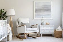 A Contemporary Rocking Chair In The Nursery Room, Painted In A Pristine Shade Of White And Featuring A Modern Design. It Is Accompanied By A Set Of Drawers For Storage, Along With Tasteful Decorations