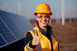 Young woman with thump up in front of a solar power plant