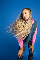 Wall Mural - charming african american woman with dreadlocks and long hair posing on blue background in studio