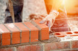 © Iryna - Industrial bricklayer laying bricks on cement mix on construction site close-up