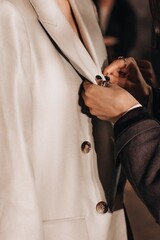 Wall Mural - Female hands preparing fashion model dressed in white classy jacket before the fashion show. Backstage preparation