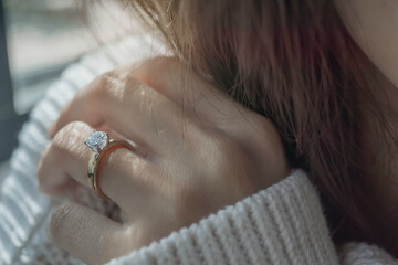 Wall Mural - Close up of diamond ring on woman’s finger with sunlight and shadow. Love, valentine, relationship and wedding concept. Soft and selective focus.