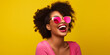 laughing young black woman with cool sunglasses in front of a yellow background