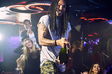 Young Man Shaking Champagne Bottle At Nightclub