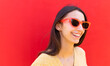 © ADDICTIVE STOCK - Smiling woman in sunglasses against red background