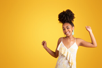 Wall Mural - Positive relaxed millennial black lady dancing, has fun alone, isolated on orange background