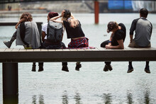 Teenage friends sitting on jetty over river