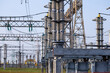A high-voltage power electrical substation. Power lines, poles, ceramic and glass insulators, lightning arresters, sulfur hexafluoride circuit breakers, current transformers.