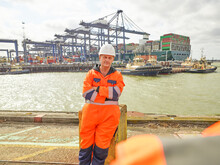 Dock Worker Relaxing Infront Of Cargo Ship Leaving Dockside