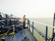 © Connect Images - Dock supervisor and crane driver surveying weather from the top of crane over cargo ship