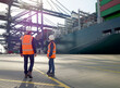 © Connect Images - Two dock workers standing by cargo cranes in dockyard, Felixstowe, England.