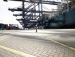 © Connect Images - Dock worker standing beneath cargo crane and ship in shadows, Felixstowe, England.