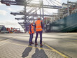© Connect Images - Two dock workers looking at cargo ship in sunlight, Felixstowe, England.