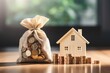 The concept of home loan or reverse mortgage and saving for real estate is represented through a house model and a US dollar money bag placed on top of coins. This signifies the idea of making saving