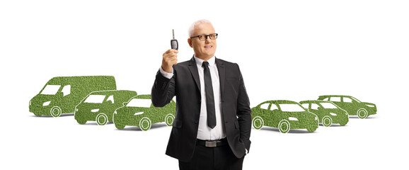 Wall Mural - Mature man with a key in front of eco-friendly vehicles