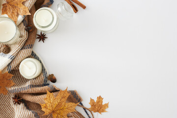 Wall Mural - Embrace the comforting and inviting fall atmosphere at home. Top view shot of candles, warm blanket, anise, acorn, cinnamon sticks, dry leaves on white background with empty space for advert or text