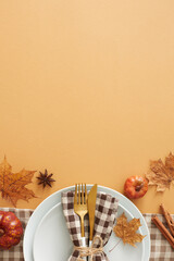 Captivating autumnal decor concept. Top view vertical shot of plate, cutlery, napkin, tablecloth, pumpkins, cinnamon sticks, anise, autumn leaves on pastel brown background with space for ads or text