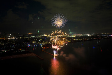 Wall Mural - Aerial view of bright fireworks exploding with colorful lights over sea shore on US Independence day holiday