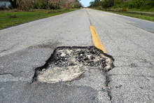 Damaged Asphalt Road With Deep Pothole On American Highway Surface. Ruined Roadway In Urgent Need Of Repair