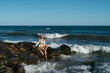 © sutulastock - A beautiful girl in white glasses and white clothes sits on the rocks on the seashore