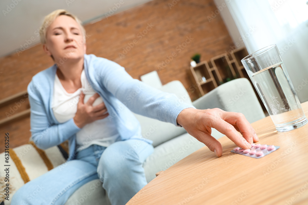 Mature woman with heart attack taking pills at home