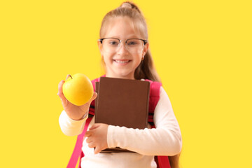 Canvas Print - Little schoolgirl with books and apple on yellow background