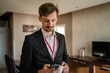 © Miljan Živković - one man adult caucasian businessman wear suit in hotel room while taking a brake or prepare for work hold cup of coffee and smartphone sending sms messages copy space