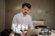 © Miljan Živković - One man adult caucasian businessman sit on the bed in hotel room work on his laptop computer prepare for meeting or remote online conference real person copy space wear white shirt